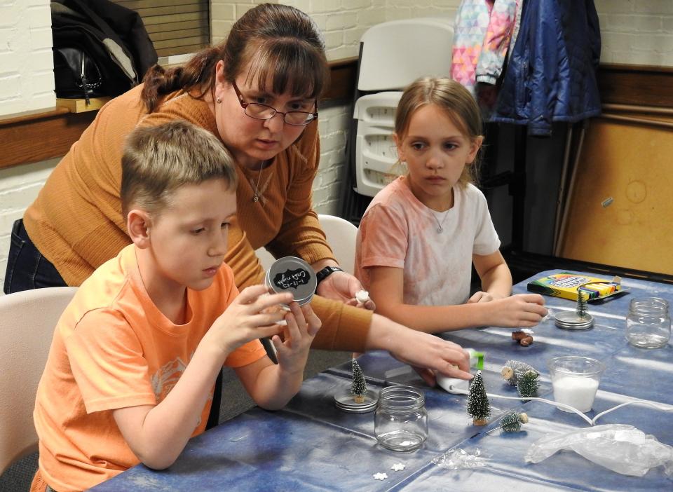 Kecia Buxton helps her children Henry Buxton, 7, and Celia Buxton, 9. Youth Services Coordinator Laiken Bantum led a snow globe craft at Coshocton Public Library. About 15 youth were registered. Kids used snowmen, animal and tree figurines and fake snow to create do-it-yourself snow globes in glass jars to take home.