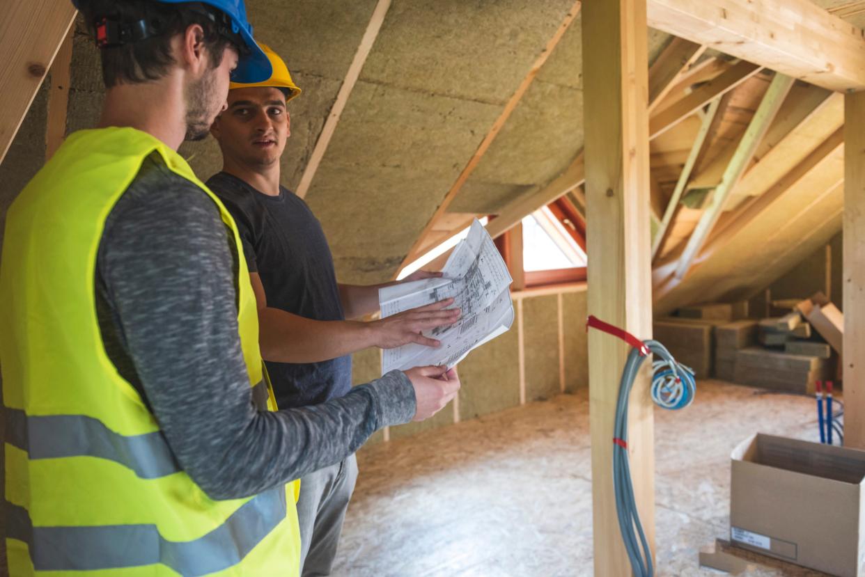 Zwei Handwerker besprechen die Dämmung eines Hausdaches mit MIneralwolle.