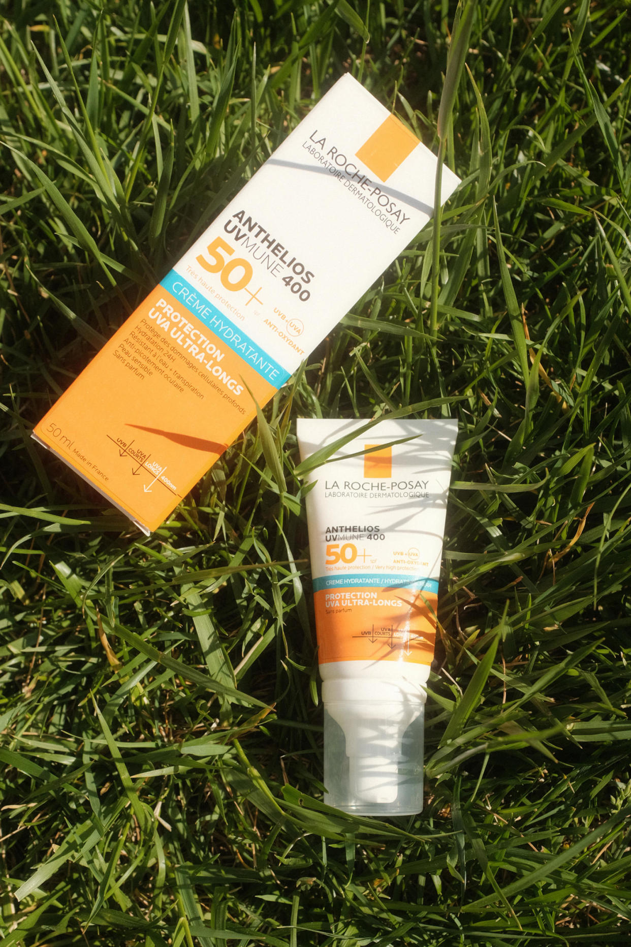 A bottle of sunscreen and its box lay in grass in the sun. (Chelsea Stahl and Elise Wrabetz / NBC News)