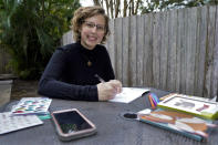 Kara McKlemurry poses for a photo while writing Thanksgiving notes to family and friends at her home Thursday, Nov. 19, 2020, in Clearwater, Fla. On any normal Thanksgiving Day, McKlemurry and her husband would drive from their home to one of two places: his family's home in another part of Florida or her family's house in Alabama. This year, McKlemurry informed her family there would be no visits because of the pandemic. (AP Photo/Chris O'Meara)