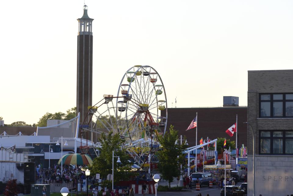 The sunset looms over carnival rides south of the 10th Street Bridge and at McMorran Place during family night festivities as part of Boat Week and Blue Water Festival in downtown Port Huron on Thursday, July 14, 2022.