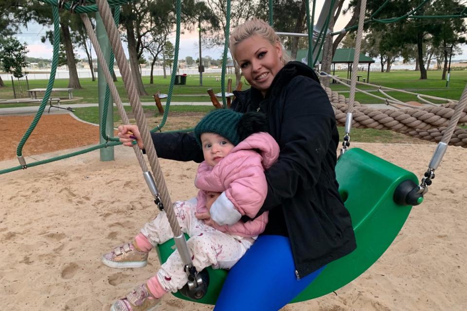 Lola and Elle Wilkinson on a swing set while bundled up in warm jackets.