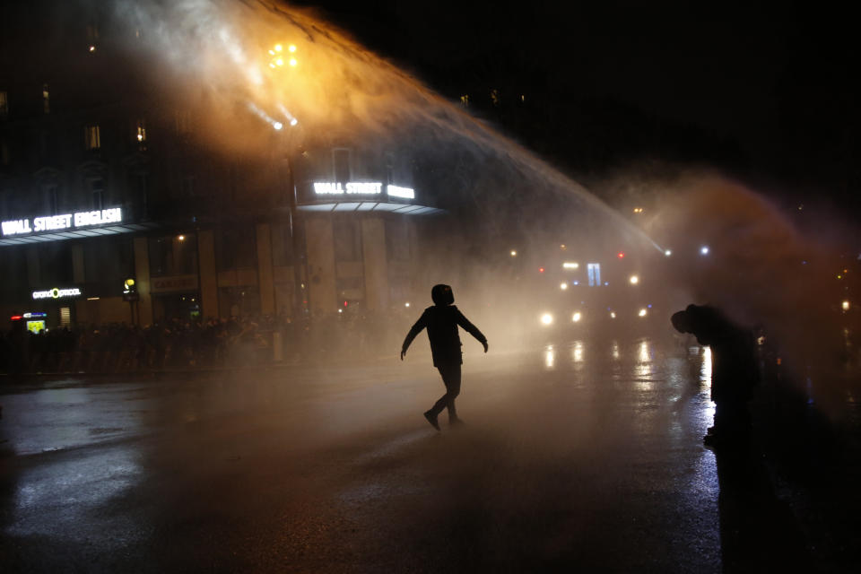 A man walks toward a police water canon during a protest against a proposed security bill, Saturday, Dec.12, 2020 in Paris. The bill's most contested measure could make it more difficult for people to film police officers. It aims to outlaw the publication of images with intent to cause harm to police. The provision has caused such an uproar that the government has decided to rewrite it. Critics fear the law could erode press freedom and make it more difficult to expose police brutality. (AP Photo/Thibault Camus)