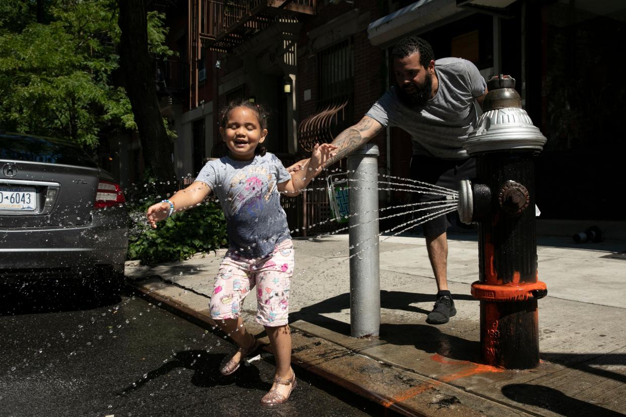 Ally Rogers, 5, plays in the spray from a fire hydrant with her father Allen, Tuesday, July 28, 2020 in New York. 