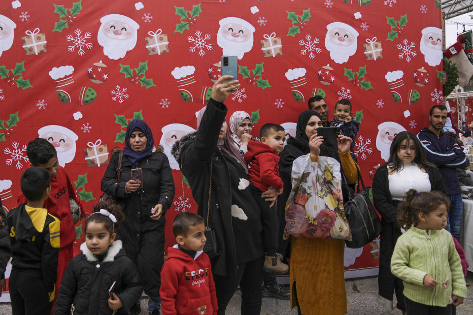 Palestinians visit the decorated Manger Square ahead of Christmas, outside to the Church of the Nativity, traditionally believed by Christians to be the birthplace of Jesus Christ, in the West Bank city of Bethlehem, Sunday, Nov. 27, 2022. Business in Bethlehem is looking up this Christmas as the traditional birthplace of Jesus recovers from a two-year downturn during the coronavirus pandemic. Streets are already bustling with visitors, stores and hotels are fully booked and a recent jump in Israeli-Palestinian fighting appears to be having little effect on the vital tourism industry. (AP Photo/ Mahmoud Illean)