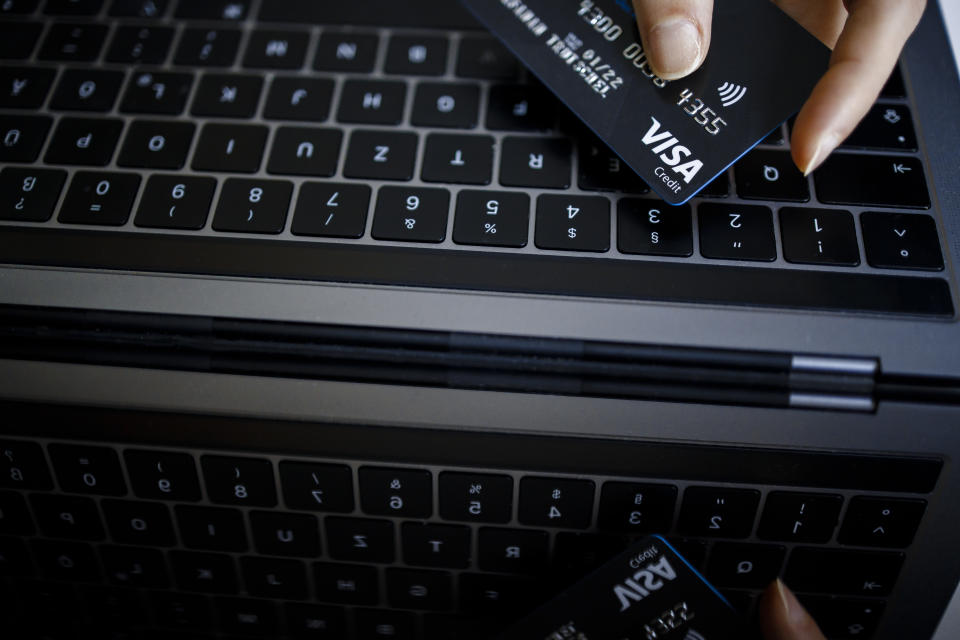 scams  BERLIN, GERMANY - FEBRUARY 02: Symbolic photo on the subject of online shopping. A VISA credit card is held next to the keyboard of a laptop. (Photo by Thomas Trutschel/Photothek via Getty Images)