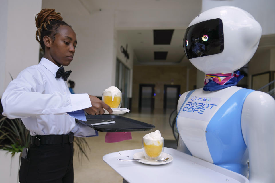 Robotic waiter Claire, receives an order from a human waiter to deliver to customers at the Robot Cafe in Nairobi, Kenya Thursday, Aug. 29, 2024. The three robots, christened Claire, R24 and Nadia, are not programmed to have a full conversation with customers, but they can say "Your order is ready, Welcome" then people have to press an exit button after picking up their food from the tray. (AP Photo/Brian Inganga)