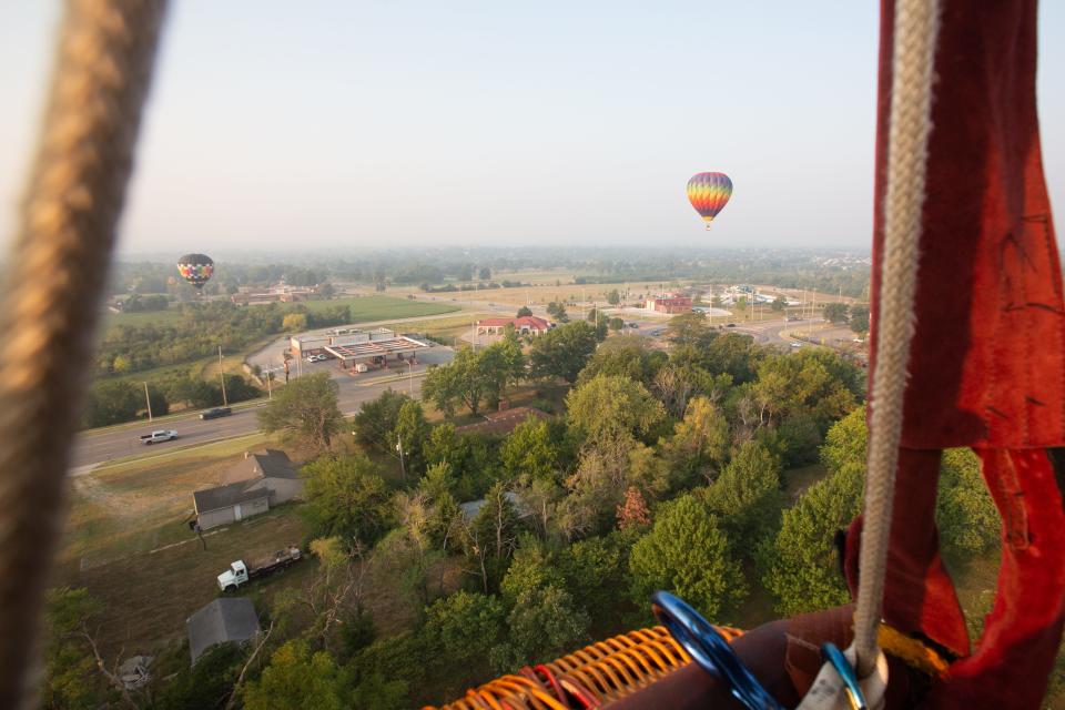 Brian Carlson's Lollygag, left, and Michael Scott's Spirit's Rainbow, start spotting their landing by the Midwest Health Aquatic Center along with Tony Goodnow's Hocus Pocus during Thursday morning's Huff 'n Puff hot air balloon media flight.