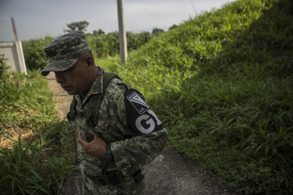 Military police wearing the insignia of the new National Guard provide perimeter security while a migration agent waits to check documents of passengers in passing transport, at an immigration checkpoint in El Manguito, south of Tapachula, Mexico, Friday, June 21, 2019. Mexico's foreign minister says that the country has completed its deployment of some 6,000 National Guard members to help control the flow of Central American migrants headed toward the U.S. (AP Photo/Oliver de Ros)