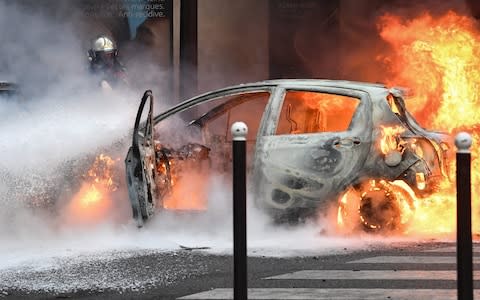 A firefighter stands next to a car set on fire during a protest of Yellow vest  - Credit: ALAIN JOCARD/AFP/Getty Images