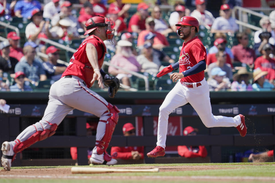 St. Louis Cardinals' Dylan Carlson, right, scores near Washington Nationals catcher Riley Adams, left, on a single hit by Paul Goldschmidt in the fifth inning of a spring training baseball game, Friday, March 25, 2022, in Jupiter, Fla. (AP Photo/Sue Ogrocki)