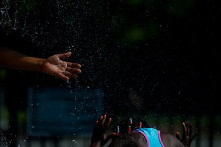 A woman and a child cool off in a park water feature in the Shaw neighbourhood during a heat wave in Washington