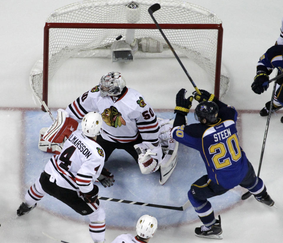 St. Louis Blues' Alexander Steen (20) scores the game-winning goal past Chicago Blackhawks goalie Corey Crawford and Niklas Hjalmarsson (4) during the third overtime in Game 1 of a first-round NHL hockey Stanley Cup playoff series Thursday, April 17, 2014, in St. Louis. The Blues won 4-3 in triple overtime. (AP Photo/Jeff Roberson)