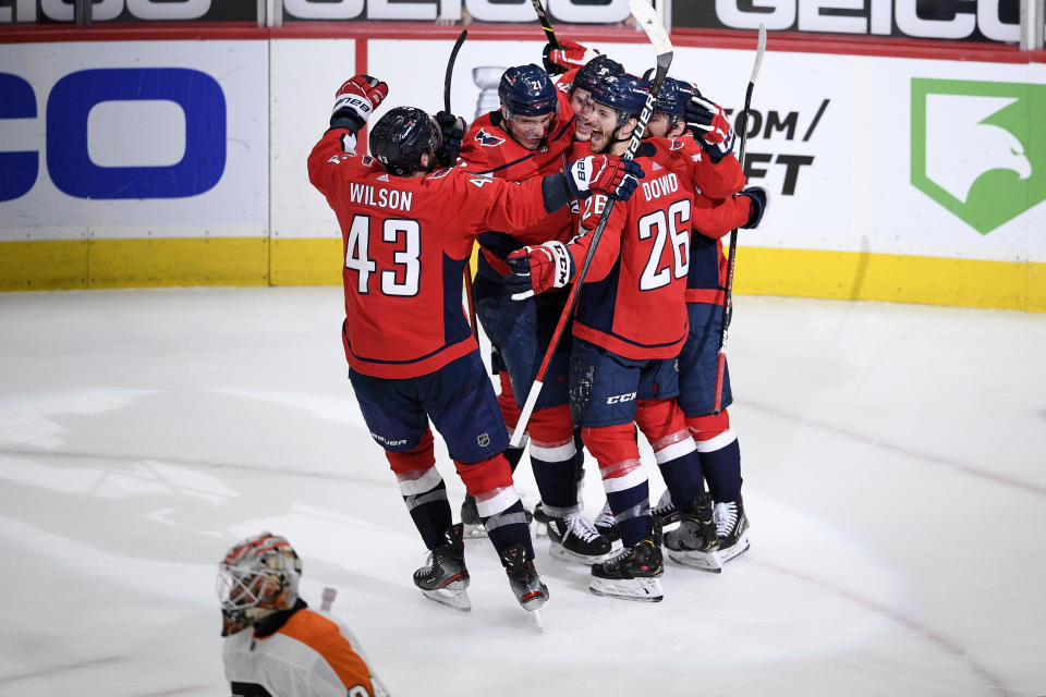 Washington Capitals right wing Tom Wilson (43), center Nic Dowd (26) and others celebrate after an NHL hockey game as Philadelphia Flyers goaltender Alex Lyon, bottom, skates away Saturday, May 8, 2021, in Washington. The Capitals won 2-1 in overtime. (AP Photo/Nick Wass)