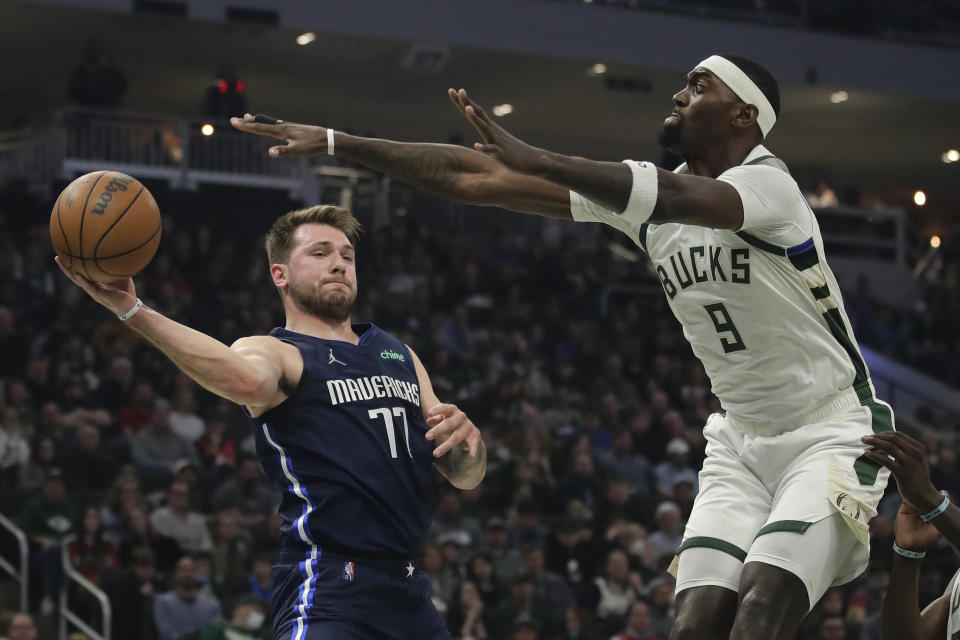 Dallas Mavericks' Luka Doncic (77) passes around Milwaukee Bucks' Bobby Portis (9) during the first half of an NBA basketball game Sunday, April 3, 2022, in Milwaukee. (AP Photo/Aaron Gash)