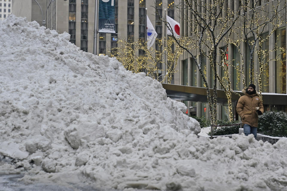 A man looks at a giant pile of snow as he walks in midtown Manhattan in New York, Tuesday, Feb. 2, 2021. Parts of northern New England are waiting their turn to be pummeled by a heavy winter storm. Tuesday's snowfall comes as residents of the New York City region are digging out from under piles of snow that shut down public transport, canceled flights and closed coronavirus vaccination sites. (AP Photo/Seth Wenig)