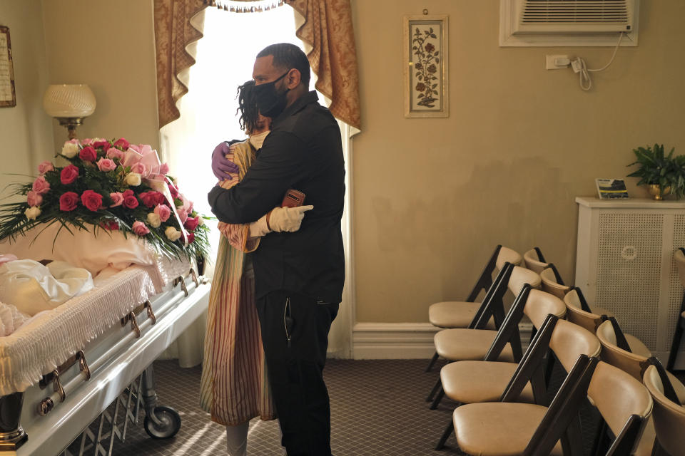 FILE - In this May 2, 2020, file photo, siblings Erika and Dwayne Bermudez comfort one another during a short viewing of their mother, Eudiana Smith, who died of coronavirus, at The Family Funeral Home in Newark, N.J. "I was robbed of the experience of being able to celebrate her life in a manner that would offer some kind of respect for the woman she was," Erika Bermudez said. She did her best, live-streaming the ceremony to friends and family who couldn't attend. (AP Photo/Seth Wenig)