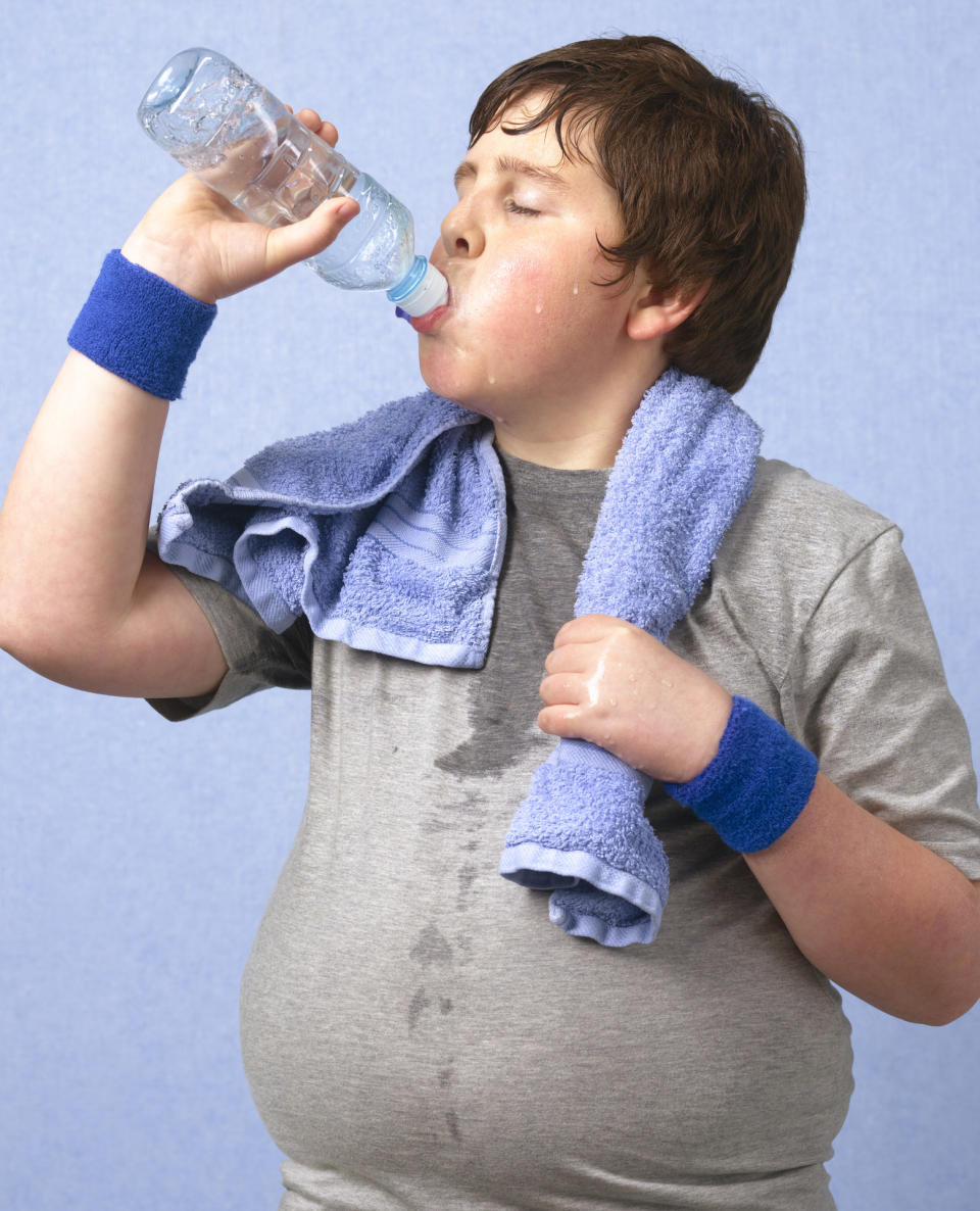 A child in exercise clothing sweating and drinking water