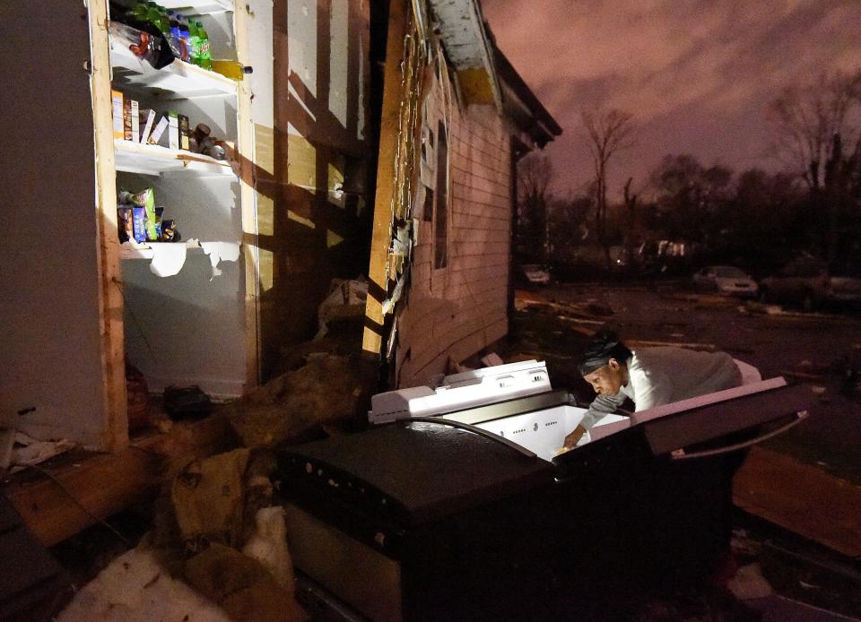 Then: A woman looks through her refrigerator after it was ripped out of her home in the Elizabeth Park neighborhood of Nashville, Tenn., on March 3, 2020.