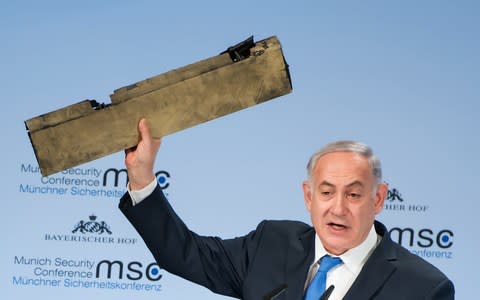 Benjamin Netanyahu holds up what he said was a piece of an Iranian drone shot down in Israeli airspace at the Munich Security Conference on Sunday - Credit: AFP PHOTO / MSC Munich Security Conference / LENNART PREISS