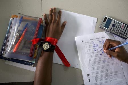 A student wears a red ribbon to express solidarity with the abducted Nigerian schoolgirls from the remote area of Chibok, as he does a maths exercise at the Regent Secondary School in Abuja, in this May 14, 2014 file photo. REUTERS/Joe Penney/Files
