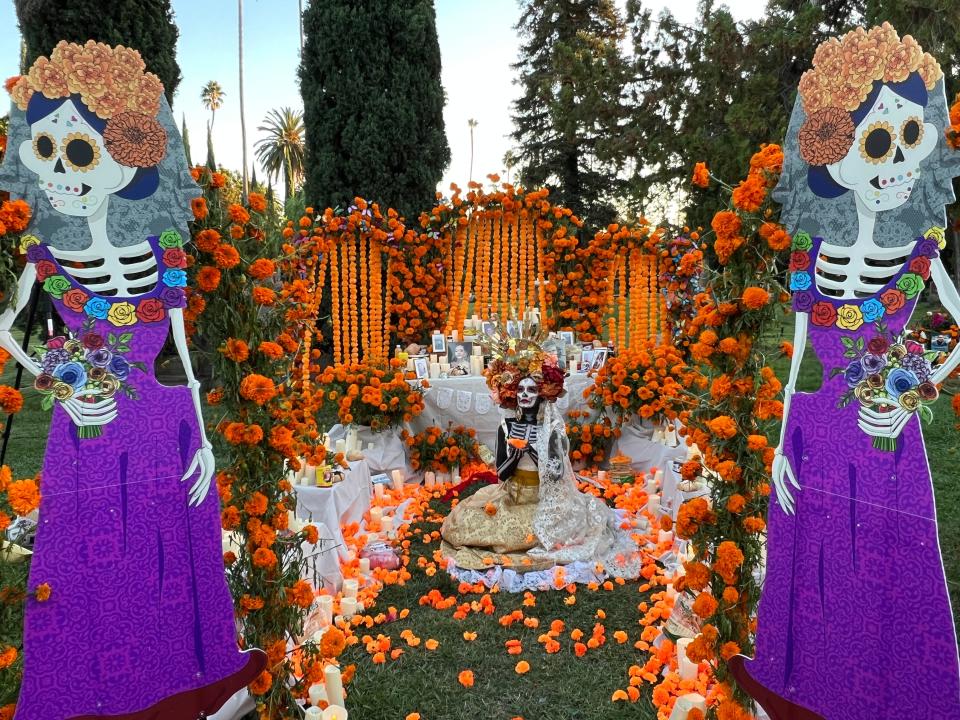 A woman dressed up as 'La Catrina' sits amid an altar to the dead at the Día de Los Muertos celebration at the Hollywood Forever Cemetery in Los Angeles on Saturday, Oct. 28, 2023.