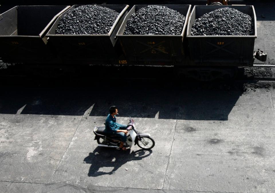 A worker rides his motorcycle near lorries transporting coal before it is loaded onto a Chinese ship at a port in Vietnam (REUTERS)