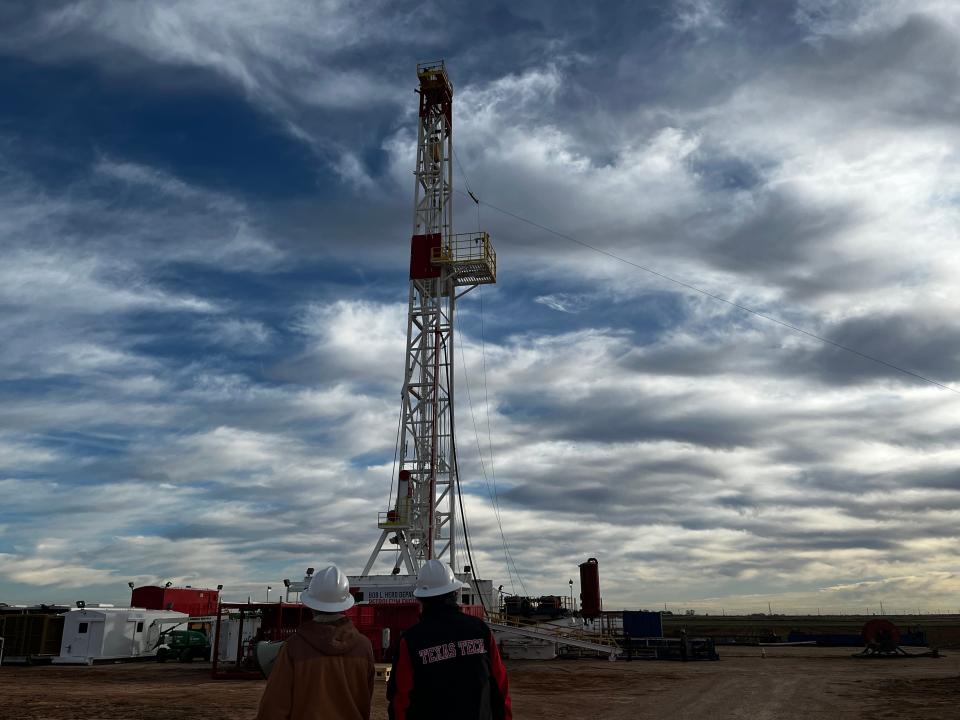 (left) Danny Bullard and Marshal Watson watching the 140-foot mast of the first operational oil rig on a university campus in the nation being raised on the Texas Tech campus.