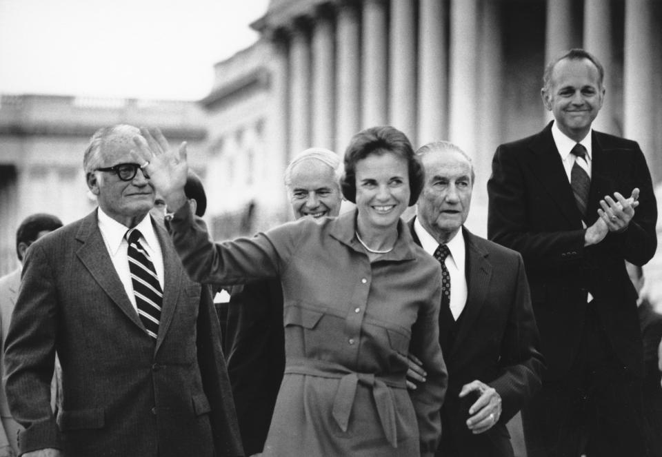 FILE - Sandra Day O'Connor waves as she arrives at the Capitol in this Sept. 10, 1981 black-and-white file photo, shortly after her nomination to the Supreme Court was confirmed by the Senate. From left, Sen. Barry Goldwater, R-Ariz., Attorney General William French Smith, O'Connor, Sen. Strom Thurmond, R-S.C., and Sen. Dennis DeConcini, D-Ariz. O'Connor, who joined the Supreme Court in 1981 as the nation's first female justice, has died at age 93. (AP Photo/Scott Applewhite, File)