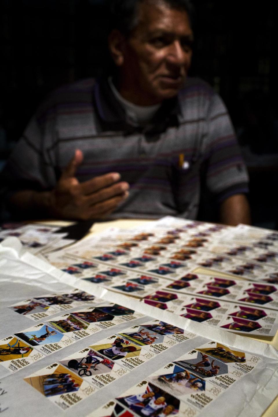 Herman Sanchez gestures to his stamps of Britain's gold Medallists collected during the 2012 Summer Olympics during an interview on Wednesday, Aug. 8, 2012, in London. London has been issuing stamps every day with photos of Britain’s gold medallists. (AP Photo/Emilio Morenatti)