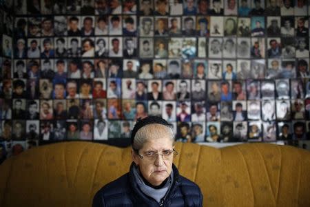 Hajra Catic poses under pictures of victims of the genocide in Tuzla, December 23, 2014. Catic lost her husband and 20 other relatives in the worst massacre on European soil since the World War Two. REUTERS/Dado Ruvic