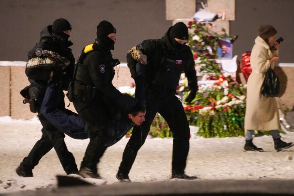 Police officers detain a man laying flowers to Alexei Navalny at the Memorial to Victims of Political Repression in St Petersburg (AP)