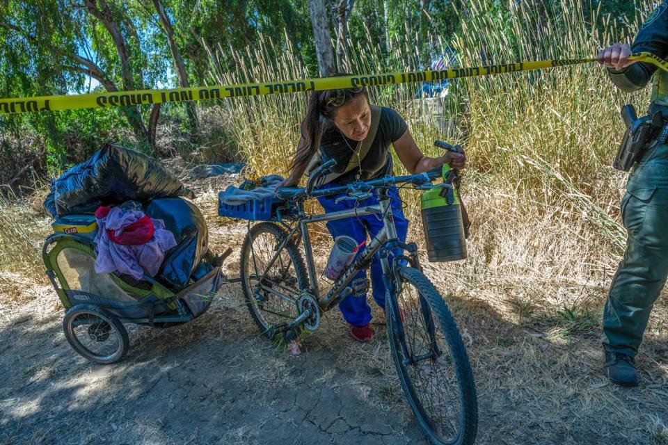 Chaming Vang, 38, ducks under police tape as she uses a bicycle cart to move some of her belongings during a sweep of a homeless encampment in Rio Linda on Monday, June 17, 2024. “We are being shoved out again. They don’t have a place for us to go, so where am I supposed to go? They gave us 48 hours to move. I work, and the thing is I can’t do all this in 48 hours. They have to give us at least 30 days. I’ve been here for ten years now,” said Vang.