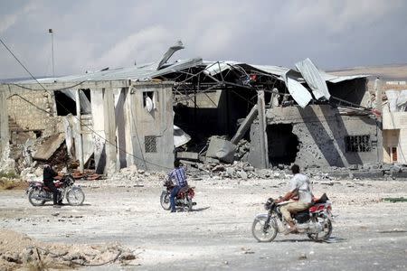 Men on motorcycles inspect a site hit by what activists said were airstrikes carried out by the Russian air force in the town of Babila, in the southern countryside of Idlib, Syria, October 7, 2015. REUTERS/Khalil Ashawi