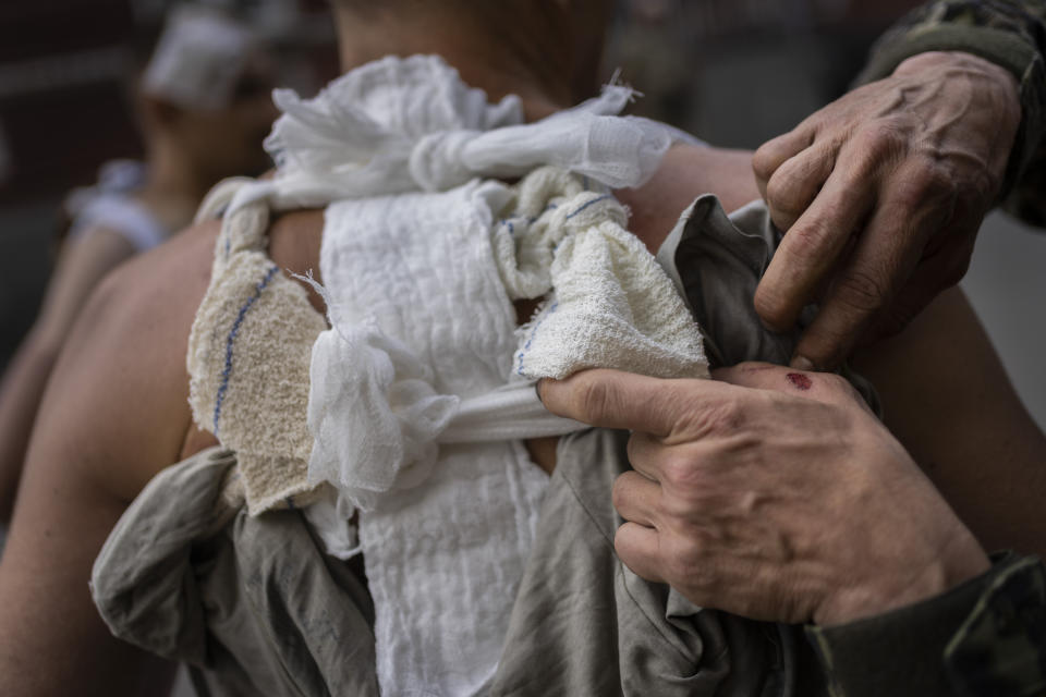 A Ukrainian serviceman adjusts the bandage to a wounded comrade in the Donetsk region, eastern Ukraine, Tuesday, June 7, 2022. (AP Photo/Bernat Armangue)