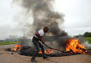 A man moves a burning barricade during protests on a road leading into Harare, Zimbabwe, January 15, 2019. REUTERS/Philimon Bulawayo