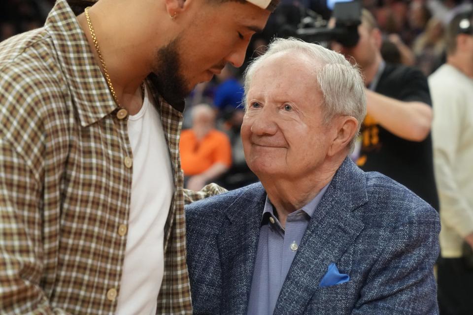 Broadcaster Al McCoy is embraced by Suns shooting guard Devin Booker after being honored for 51 seasons as "Voice of the Suns" during halftime against the Los Angeles Clippers on April 9, 2023, at Footprint Center in Phoenix.