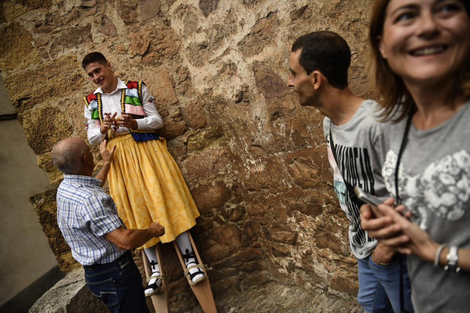 <p>An assistant helps a dancer to prepare for taking part in stilts performance in honor of Saint Mary Magdalene in a street for the traditional “Danza de Los Zancos” (Los Zancos Dance), in the small town of Anguiano, northern Spain, July 23, 2016. (AP Photo/Alvaro Barrientos)</p>