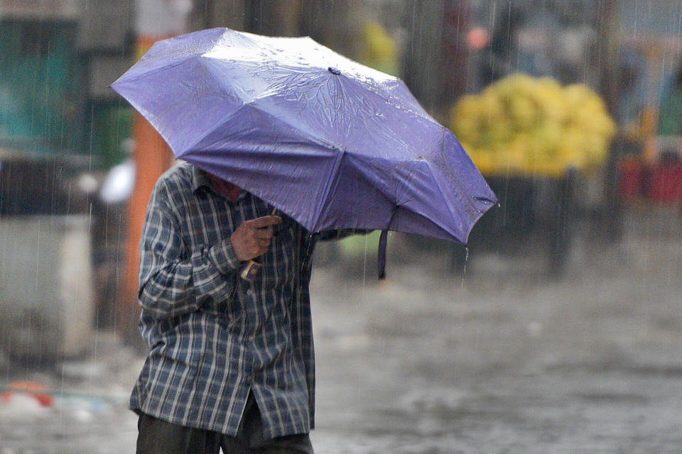 NEW DELHI, INDIA - MAY 15: A man shelters under an umbrella during rain and thunder showers in the morning, on May 15, 2019 in New Delhi, India. Parts of Delhi-NCR witnessed heavy rain bringing some relief to Delhiites from scorching heat even as dust storms hit some areas of the city. As per the India Meteorological Department, the thunderstorm activity is likely to continue over parts of northwest India for the next three-four days, due to the passage of frequent western disturbances. (Photo by Burhaan Kinu/Hindustan Times via Getty Images)