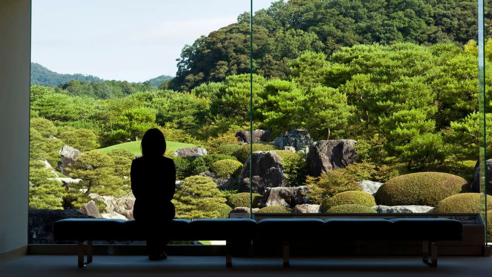 A visitor stands in front of a "frame"-style window designed to center the garden. - Robert Gilhooly/Alamy Stock Photo