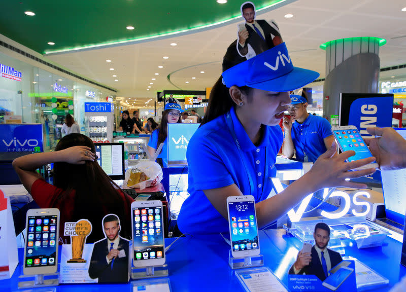 A sales person shows a buyer the features of Vivo mobile phone displayed at a stall inside a Cyberzone of the SM Mall of Asia in Pasay city, metro Manila, Philippines July 7, 2017. REUTERS/Romeo Ranoco/Files