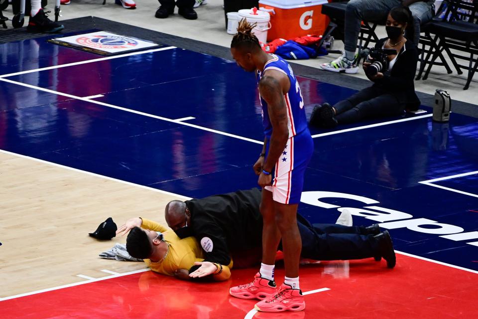 A fan is tackled by security on the floor as Dwight Howard looks on in the second half of Game 4 of the 76ers-Wizards playoff series at Capital One Arena.