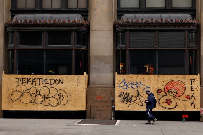 A man passes by a boarded up retail store, during the outbreak of the coronavirus disease (COVID-19) in New York