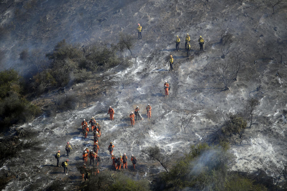 Hand crews work a wildfire-damaged hillside as the Getty fire burns on Mandeville Canyon, Oct. 28, 2019, in Los Angeles. (AP Photo/Marcio Jose Sanchez)