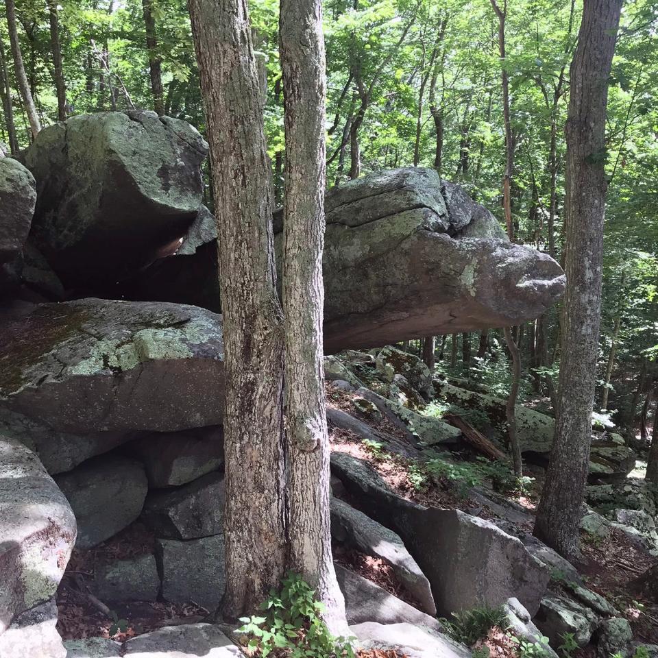 A long, thin slab of rock juts from the ledges and points like a finger above the hillside.