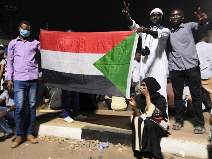 Protesters hold the national flag, after Sudan's police on Tuesday ordered officers to avoid intervening against protesters (AFP Photo/-)