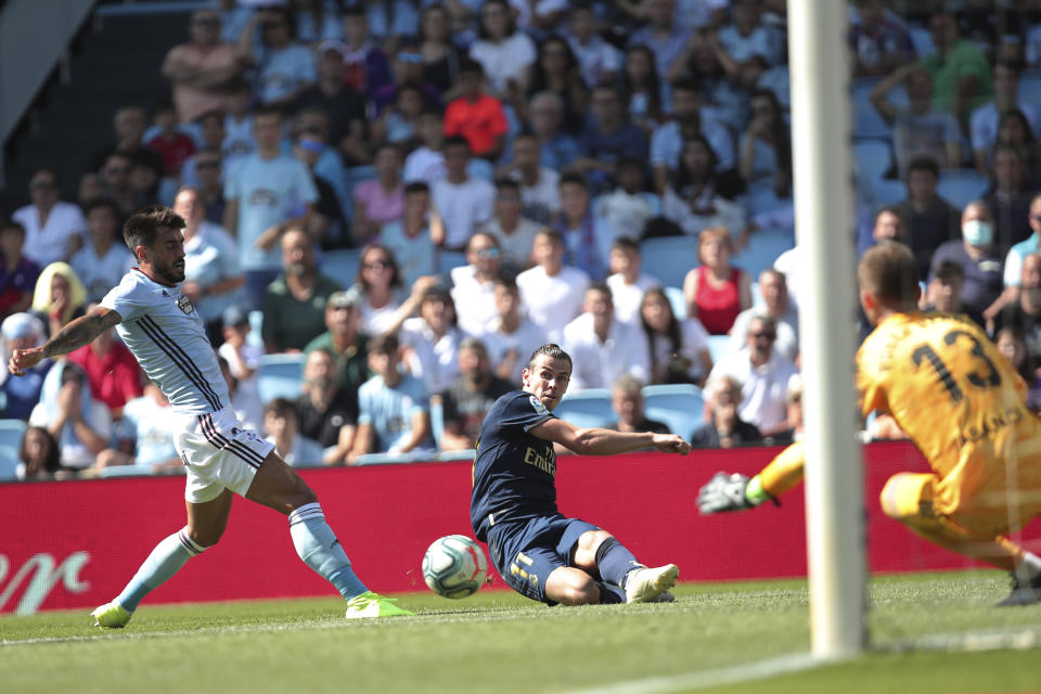 Real Madrid's Gareth Bale, centre, slides in to connect with the ball during La Liga soccer match between Celta and Real Madrid at the Balaídos Stadium in Vigo, Spain, Saturday, Aug. 17, 2019. (AP Photo/Luis Vieira)