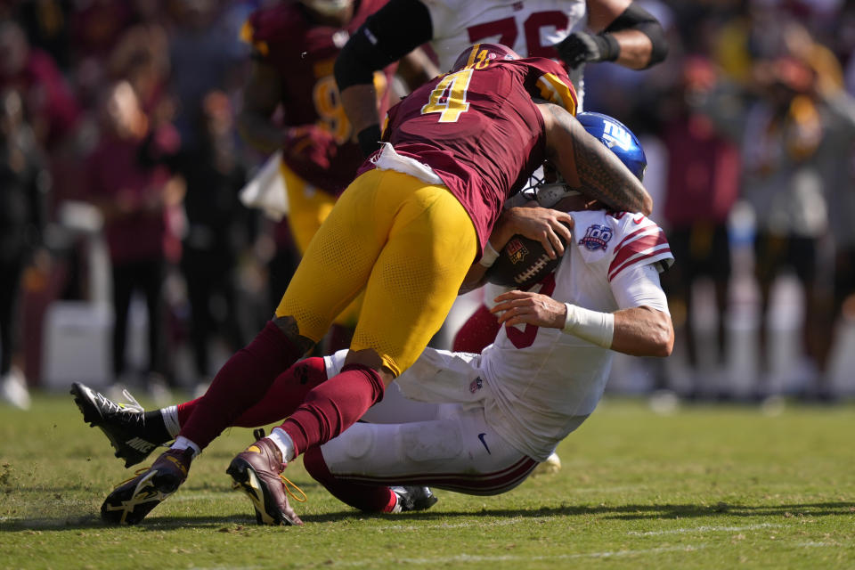 New York Giants quarterback Daniel Jones (8) is hit by Washington Commanders linebacker Frankie Luvu (4) during the second half of an NFL football game in Landover, Md., Sunday, Sept. 15, 2024. (AP Photo/Matt Slocum)