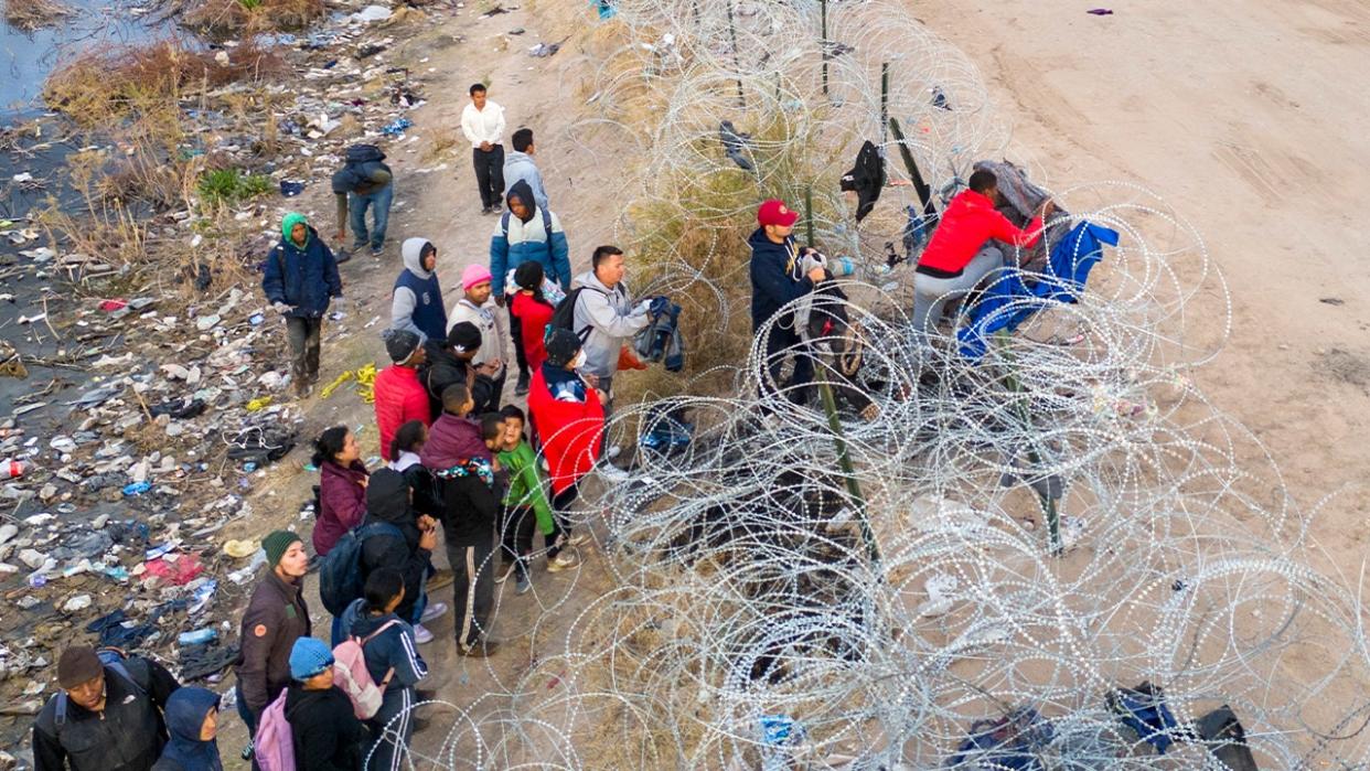 Seen from an aerial view, immigrants try to pass over razor wire after crossing the border into El Paso, Texas from El Paso, Texas. Those who managed to get through the wire were then allowed to proceed for further processing by U.S. Border Patrol agents.