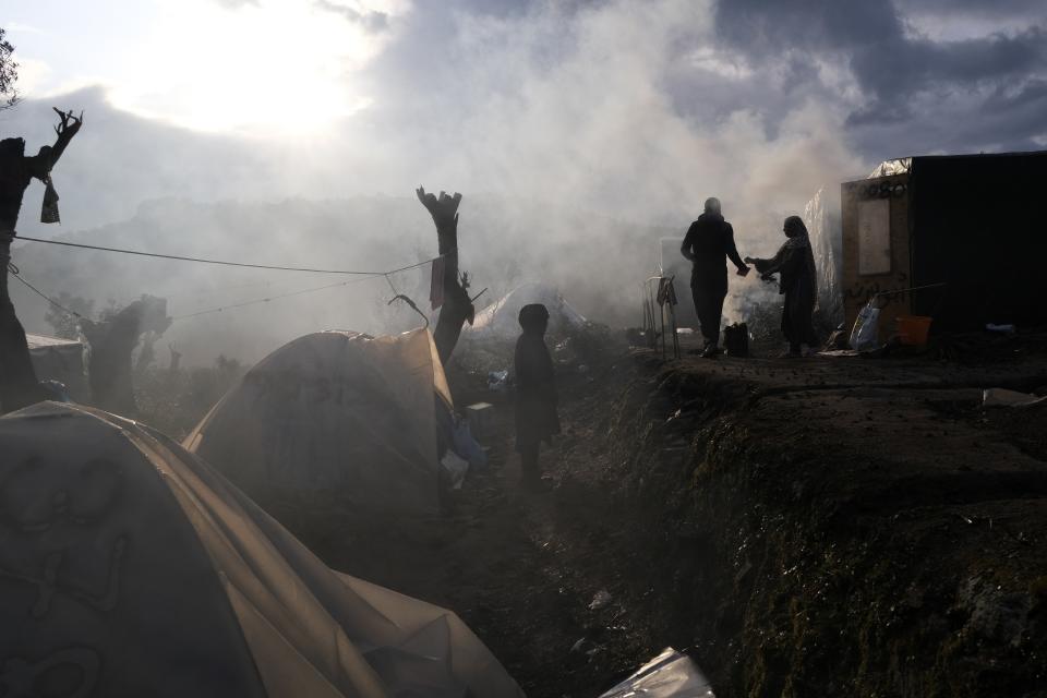 Migrants stand outside their makeshift tents outside the perimeter of the overcrowded Moria refugee camp on the northeastern Aegean island of Lesbos, Greece, Tuesday, Jan. 28, 2020. Greece has been the first point of entry into the European Union for hundreds of thousands of people fleeing war or poverty at home, with most arriving on eastern Aegean islands from nearby Turkey. (AP Photo/Aggelos Barai)